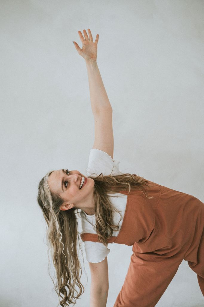 Yoga teacher in a terracotta jumpsuit performing triangle pose